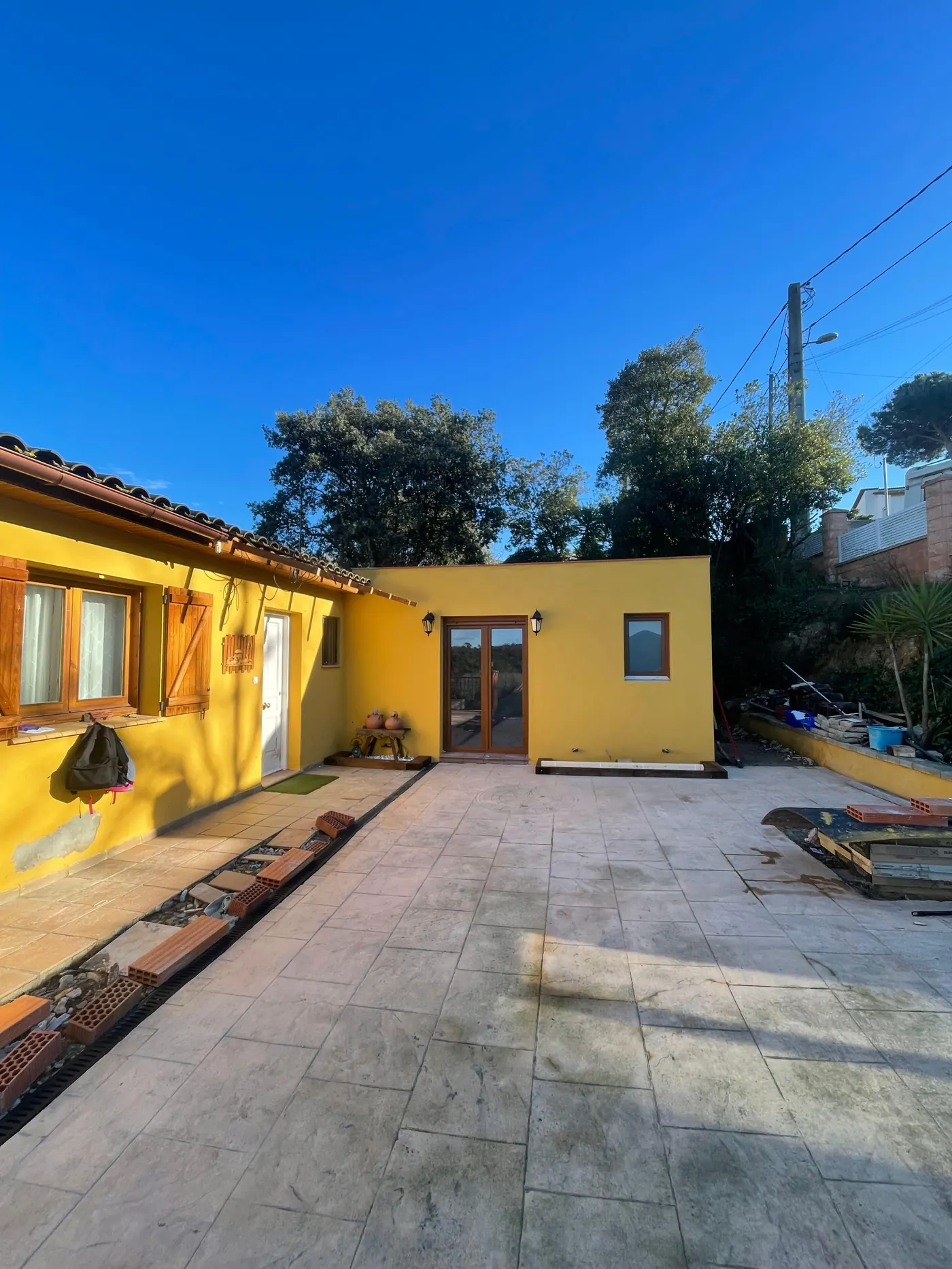 Vivienda terminada tras la ampliación, fachada pintada y patio acabado, obra de Gasparini Construcciones