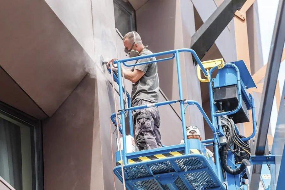 Trabajador de Gasparini Construcciones rehabilitando una fachada desde una plataforma elevadora