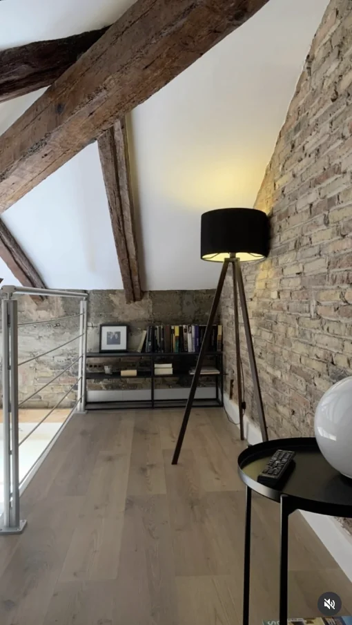 Interior restaurado con vigas de madera vistas, pared de obra vista y suelo de madera, ejemplo de restauración