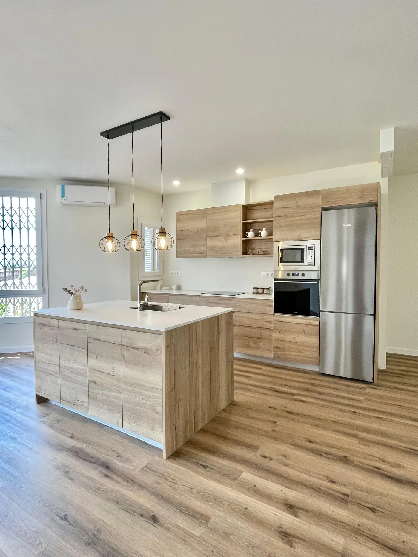 Cocina reformada por Gasparini Construcciones, con isla de madera y electrodomésticos integrados