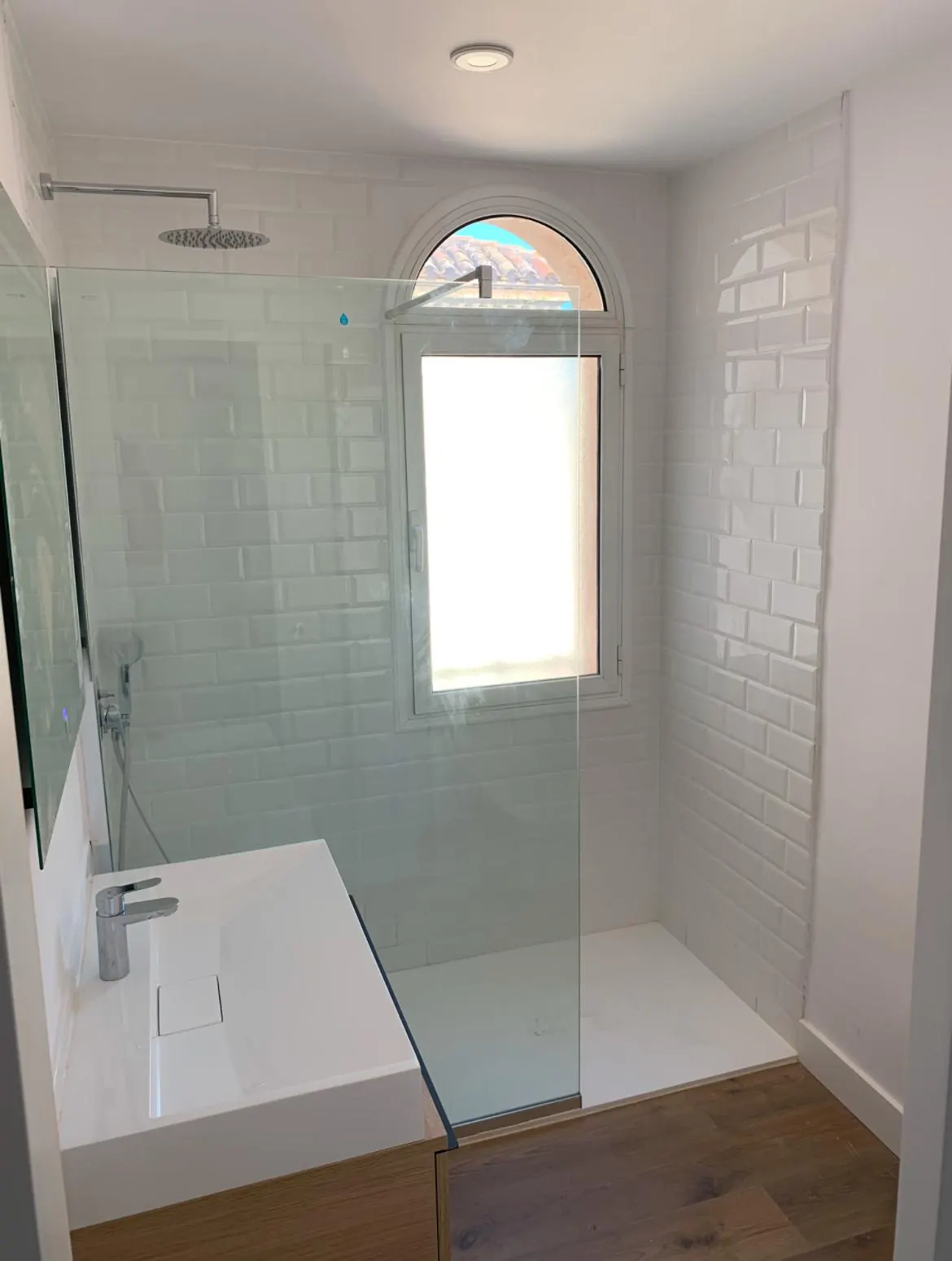 Ducha de obra en baño reformado, con alicatado blanco, obra de Gasparini Construcciones