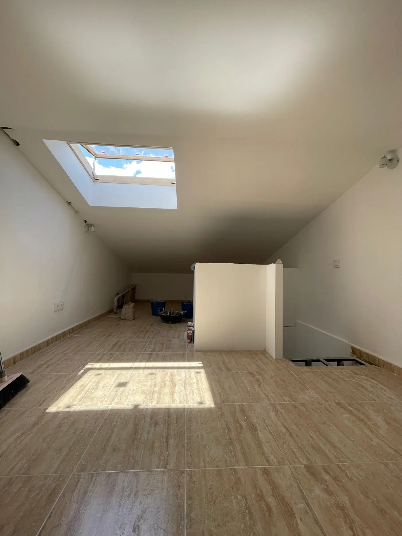 Buhardilla reformada con ventana de tejado y suelo de madera, obra de Gasparini Construcciones